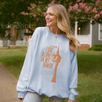 Woman wearing a light blue sweatshirt with a graphic of a tower and the words "all this time i sat alone in my tower"