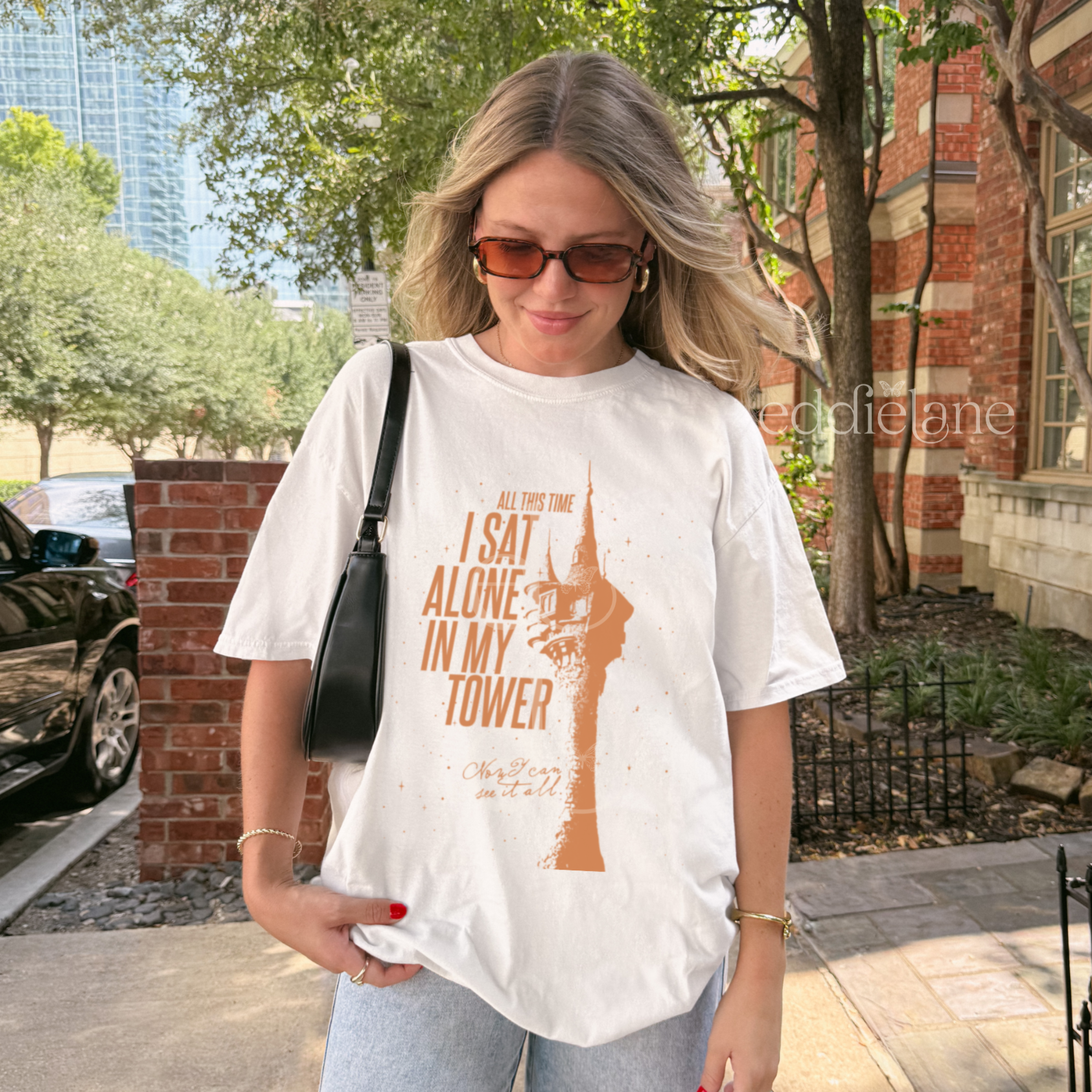 woman wearing a white comfort colors shirt with a graphic of a tower and the words "all this time i sat alone in my tower"