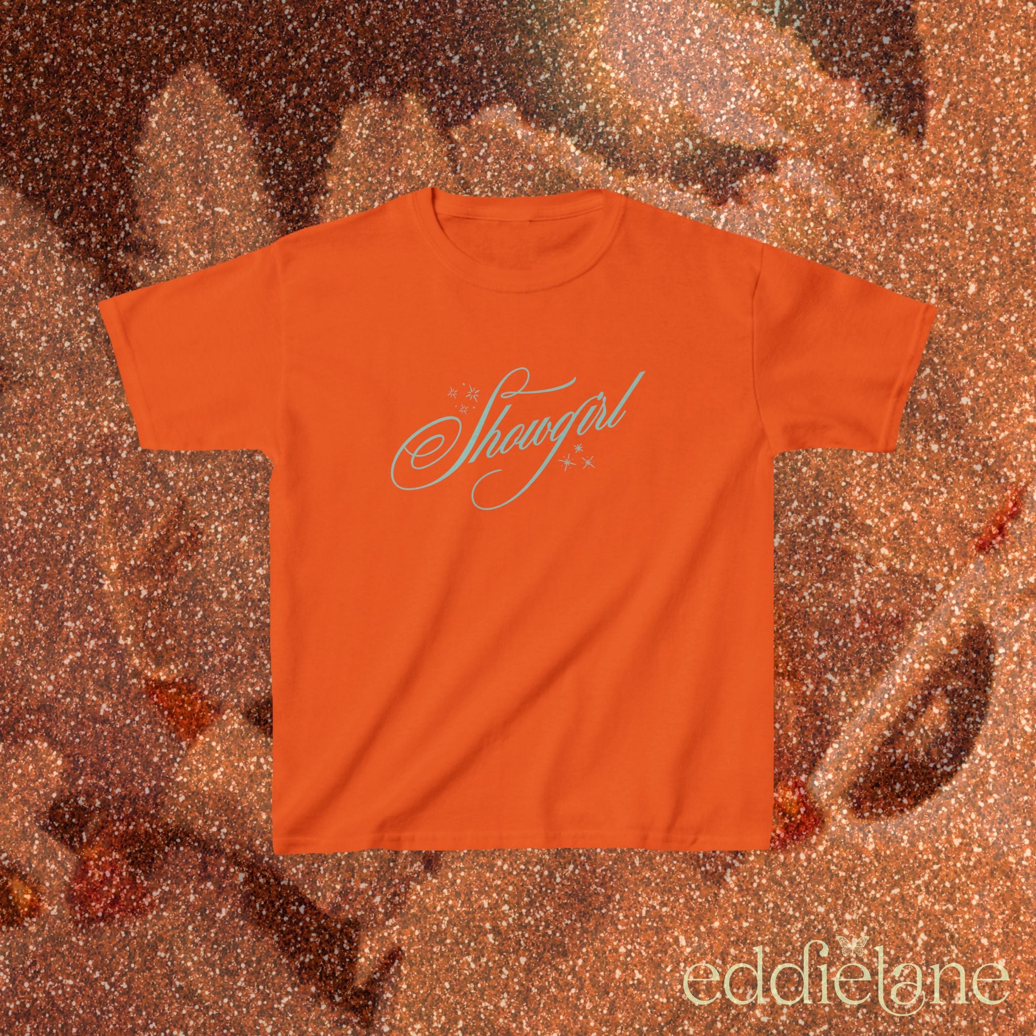 an orange baby tee with cursive text that says 'Showgirl' 

orange baby tee