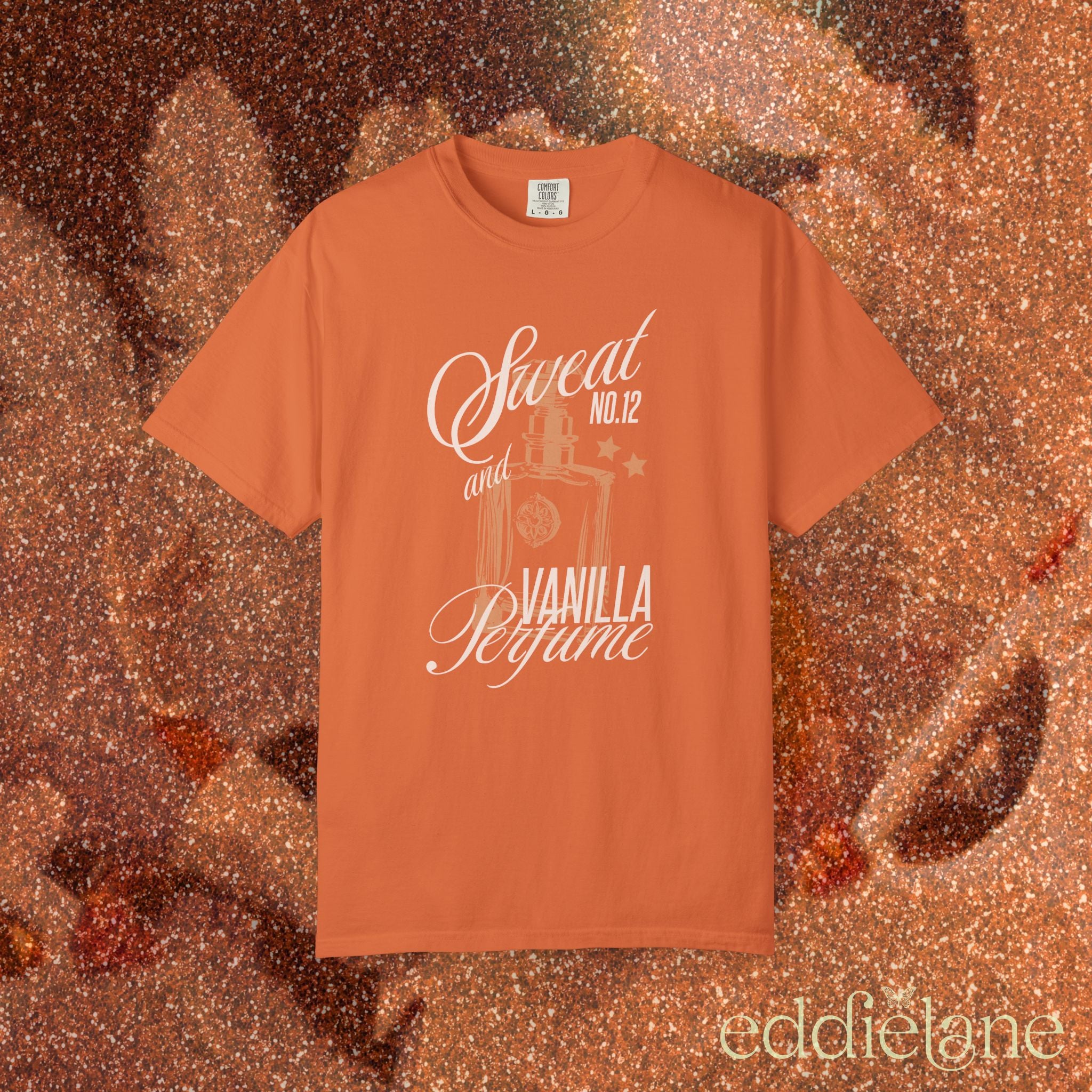 woman wearing an orange comfort colors graphic tee with an illustration of a perfume bottle and the words "sweat and vanilla perfume" 