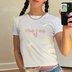 Woman wearing a white baby tee with the words "Pretty and Witty" and a small bouquet of flowers