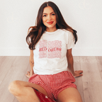 Woman wearing a light gray baby tee with "red dress" written in a curvy design