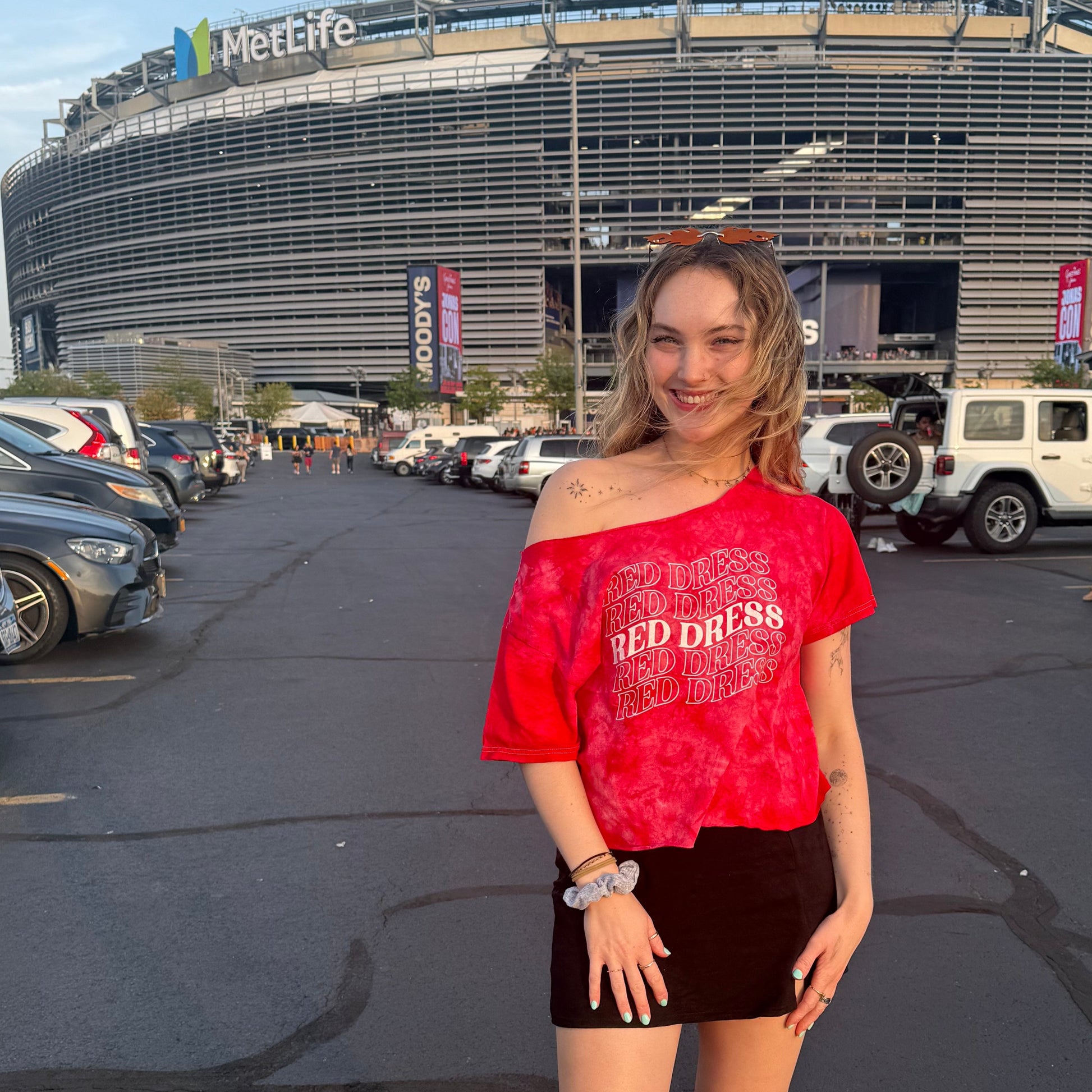 Woman wearing a red tie-dye shirt that says "red dress" in curvy lettering inspired by "burnin' up" by the jonas brothers.