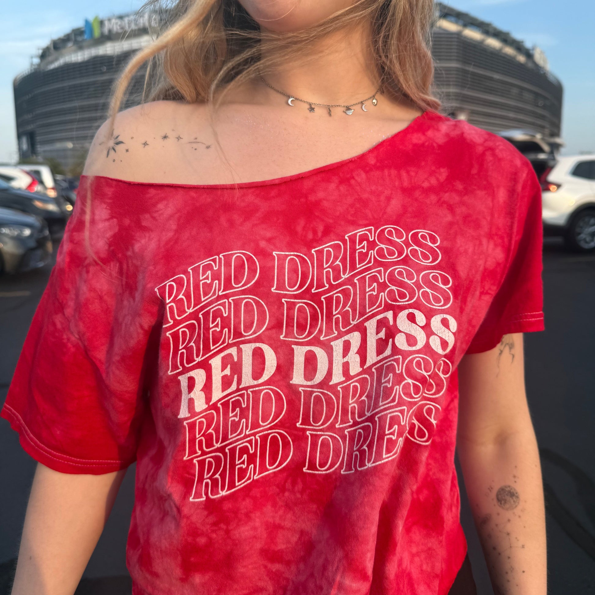 Woman wearing a red tie-dye shirt that says "red dress" in curvy lettering inspired by "burnin' up" by the jonas brothers.
