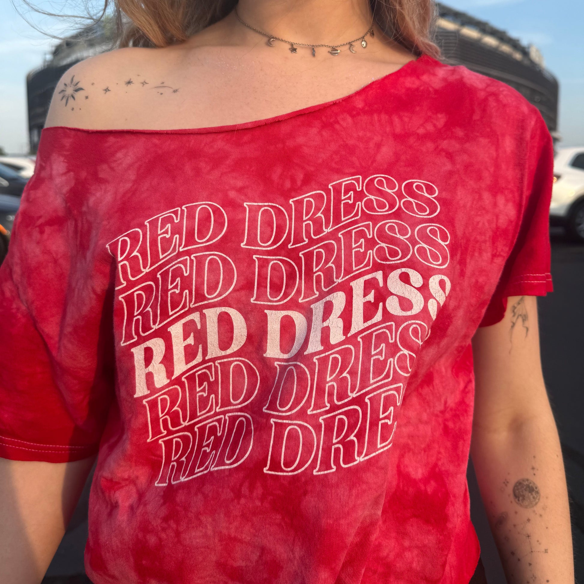 Woman wearing a red tie-dye shirt that says "red dress" in curvy lettering inspired by "burnin' up" by the jonas brothers.