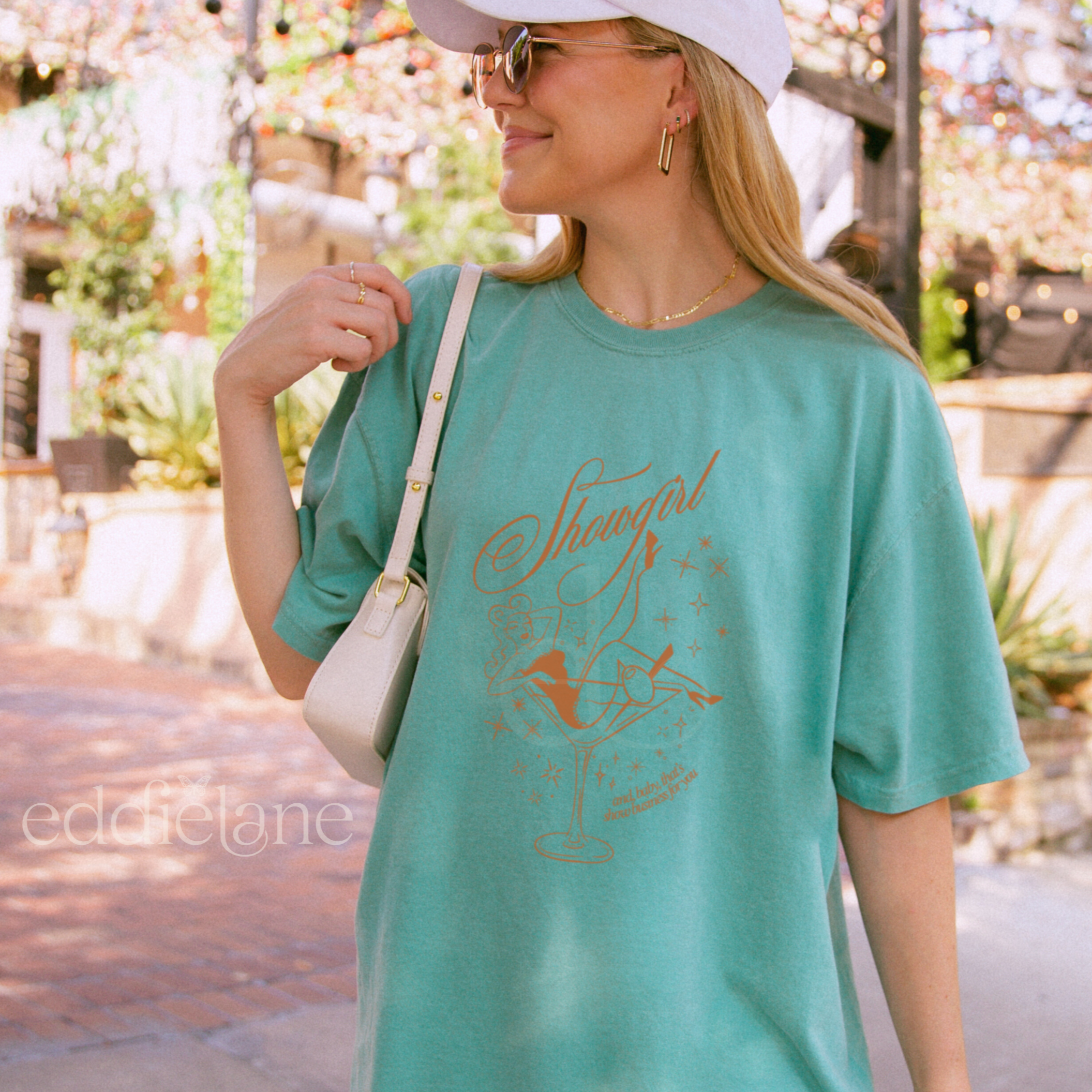 Woman wearing an oversized green t-shirt with a graphic of a showgirl in a martini glass