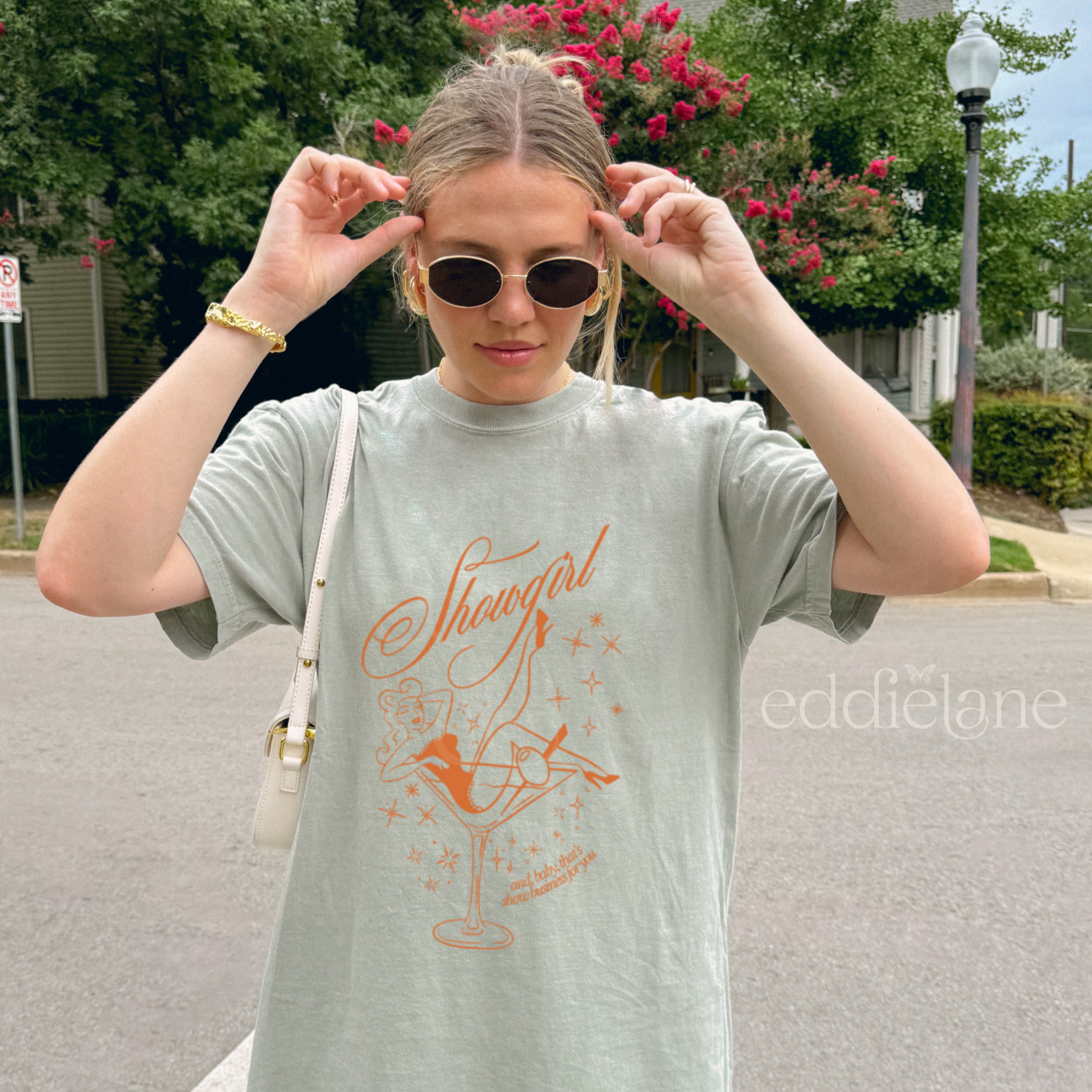 Woman wearing an oversized green t-shirt with a graphic of a showgirl in a martini glass