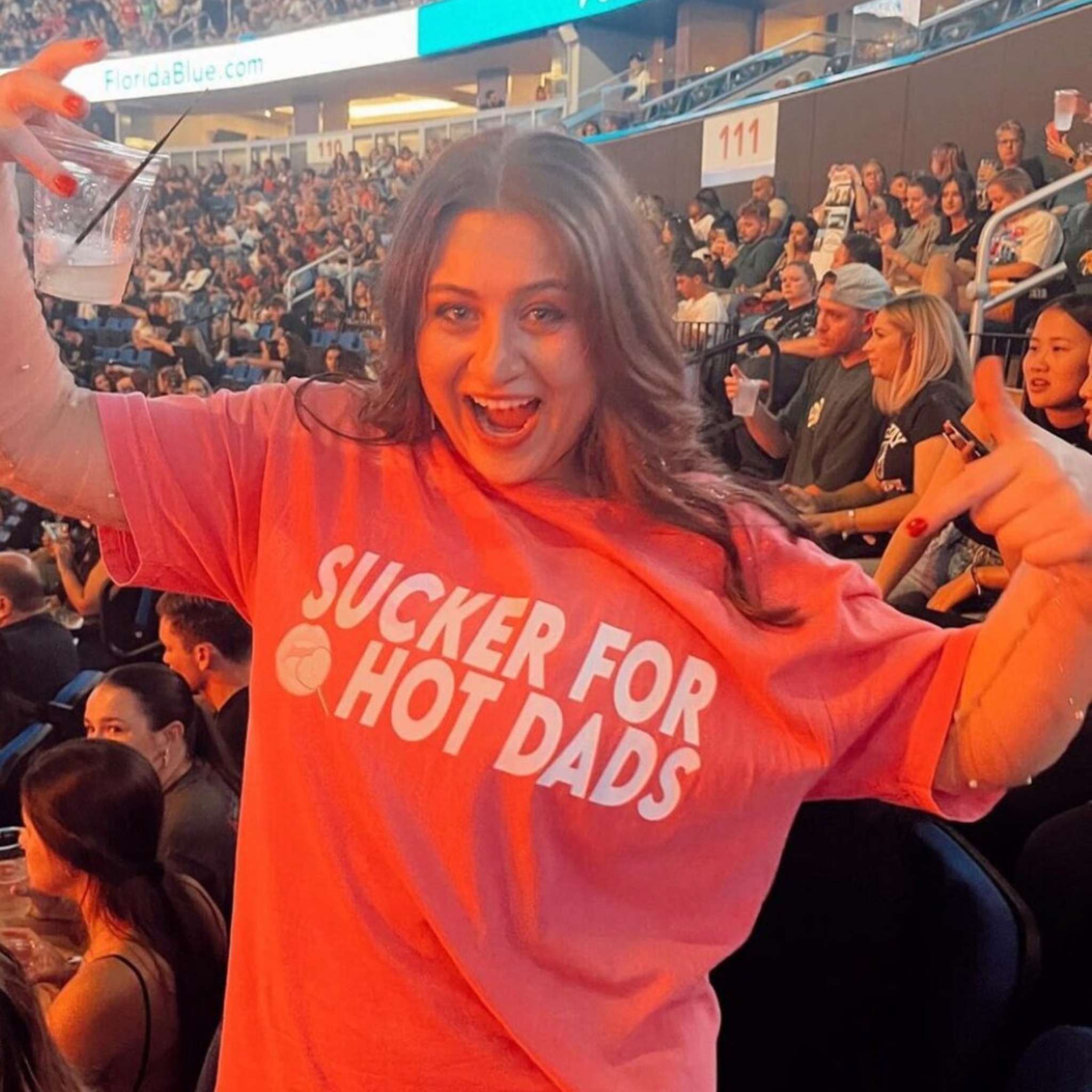 Woman in an oversized pink comfort colors t-shirt that says "sucker for hot dads"