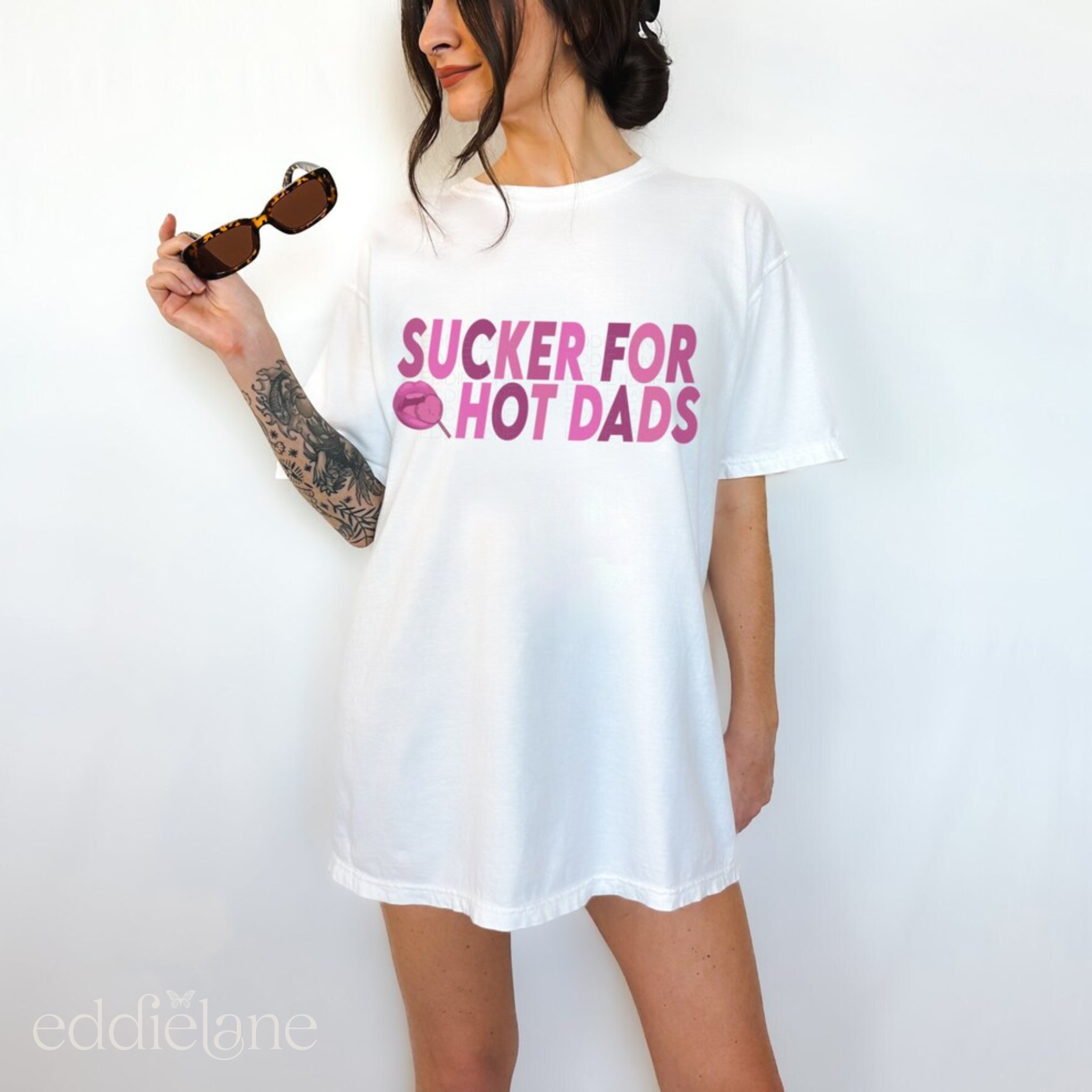 Woman in an oversized white comfort colors t-shirt that says "sucker for hot dads".