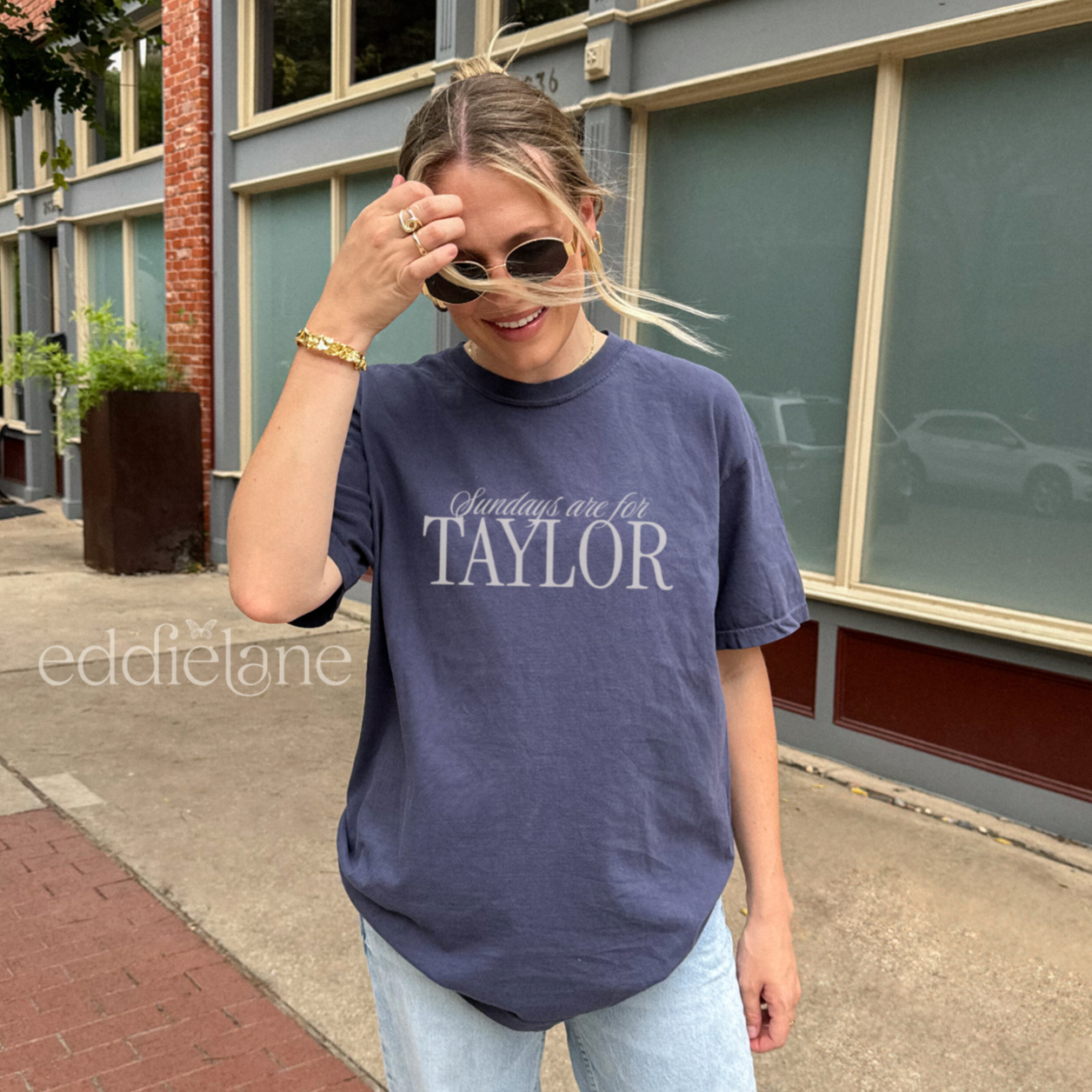 Woman wearing a navy comfort colors t-shirt that says 'Sundays are for Taylor' 