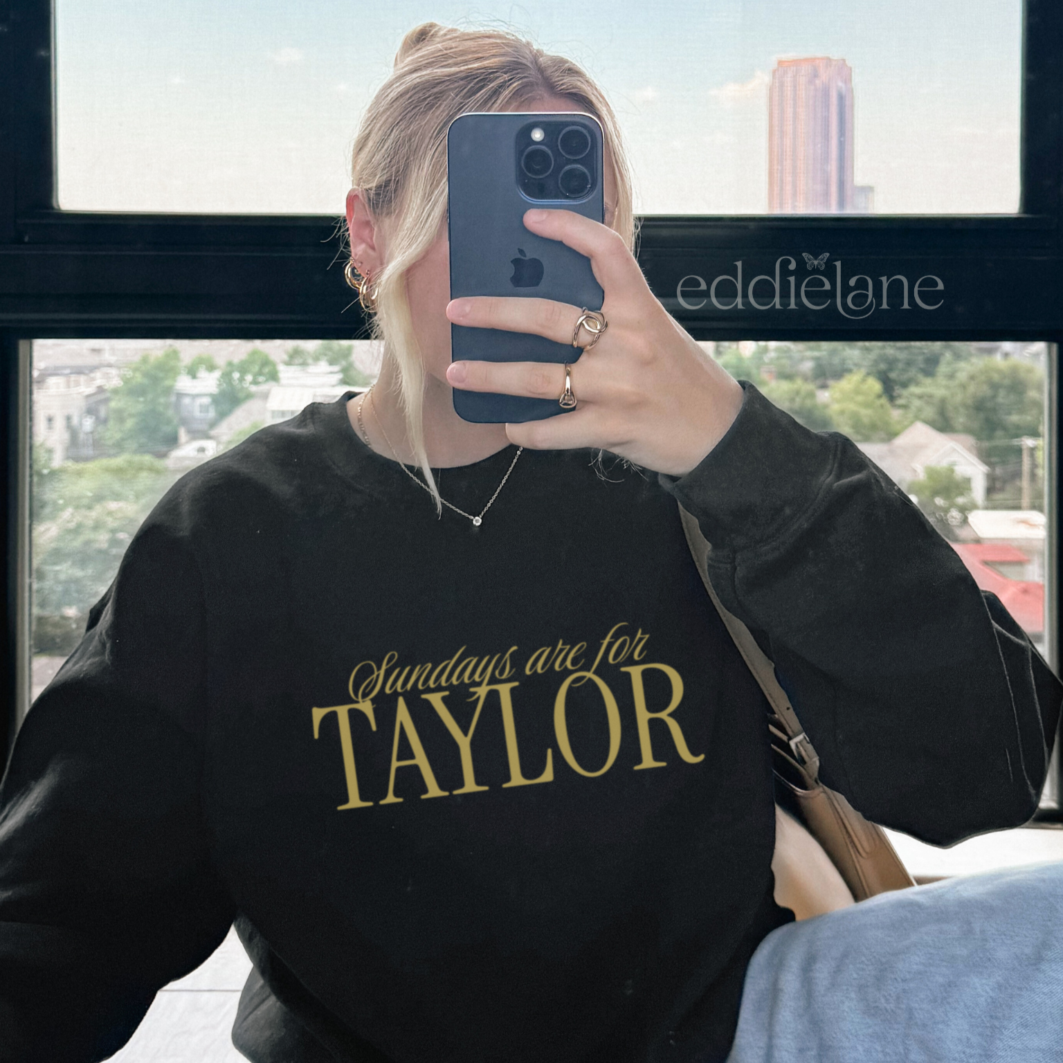 Woman wearing a black crewneck sweatshirt that says 'Sundays are for Taylor' 