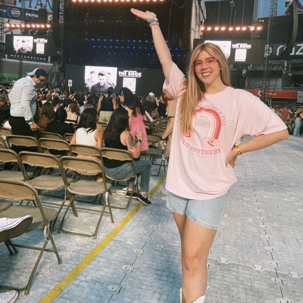 Woman in a pink oversized graphic tee that says "sweet mama it's the jonas brothers" 