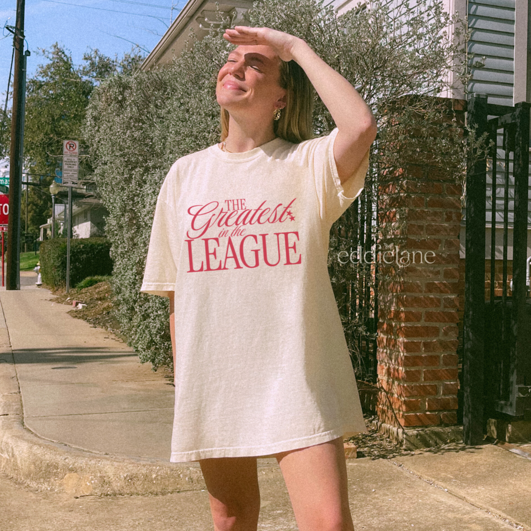 a woman in an ivory Comfort Colors t-shirt that says 'the greatest in the league' 