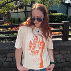 woman wearing an ivory comfort colors shirt with a graphic of a tower and the words "all this time i sat alone in my tower"