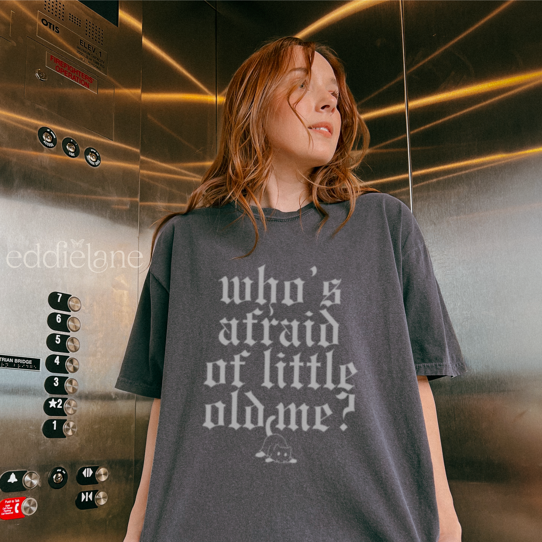 Woman wearing a pepper comfort colors t-shirt that says "who's afraid of little old me" with a graphic of a cat wearing a ghost costume