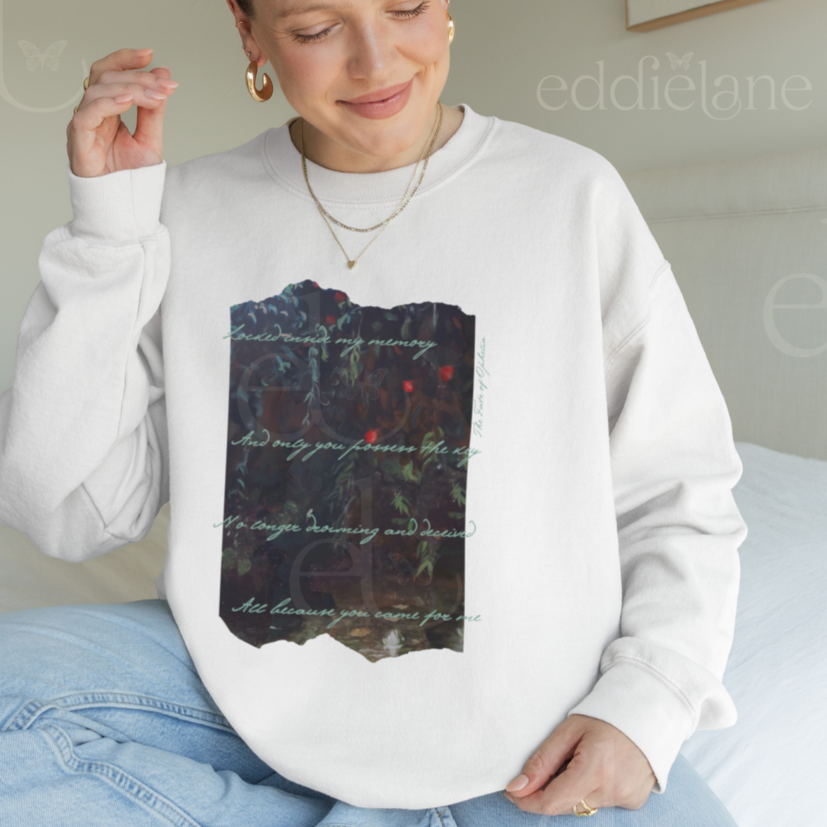 Woman wearing a white sweatshirt with a picutre of a painting and the words "Locked inside my memory and only you possess the key no longer drowning and deceived all because you came for me"