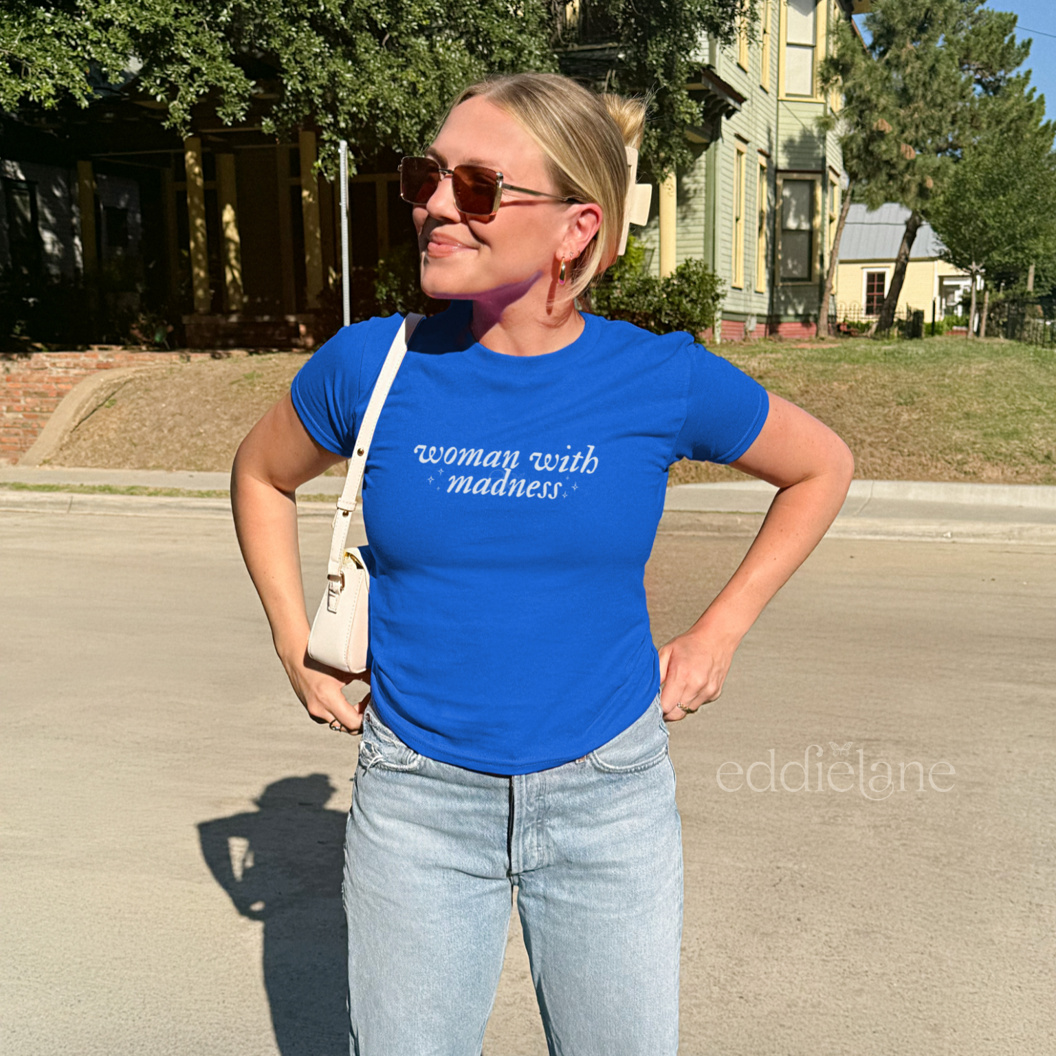 Woman wearing a royal blue baby tee with words "woman with madness" inspired by the last great american dynasty from folklore by taylor swift.
