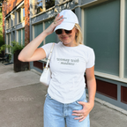 Woman wearing a white baby tee with words "woman with madness" 